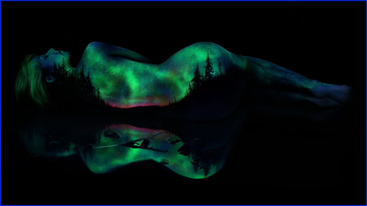 Konstnär målar med fluorescerande färg på nakna kvinnor